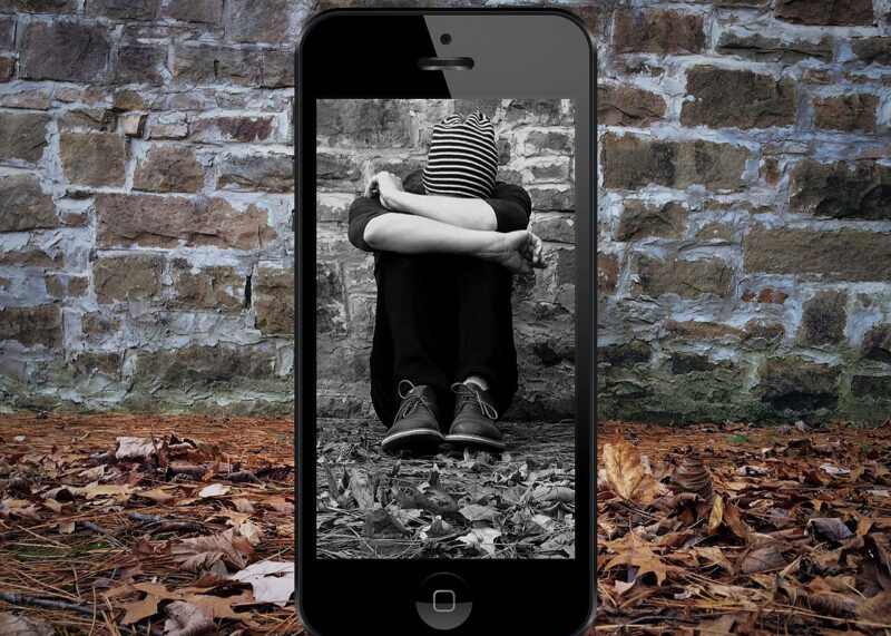 Opfer sitzt auf dem Boden und wird von Handy gefilmt